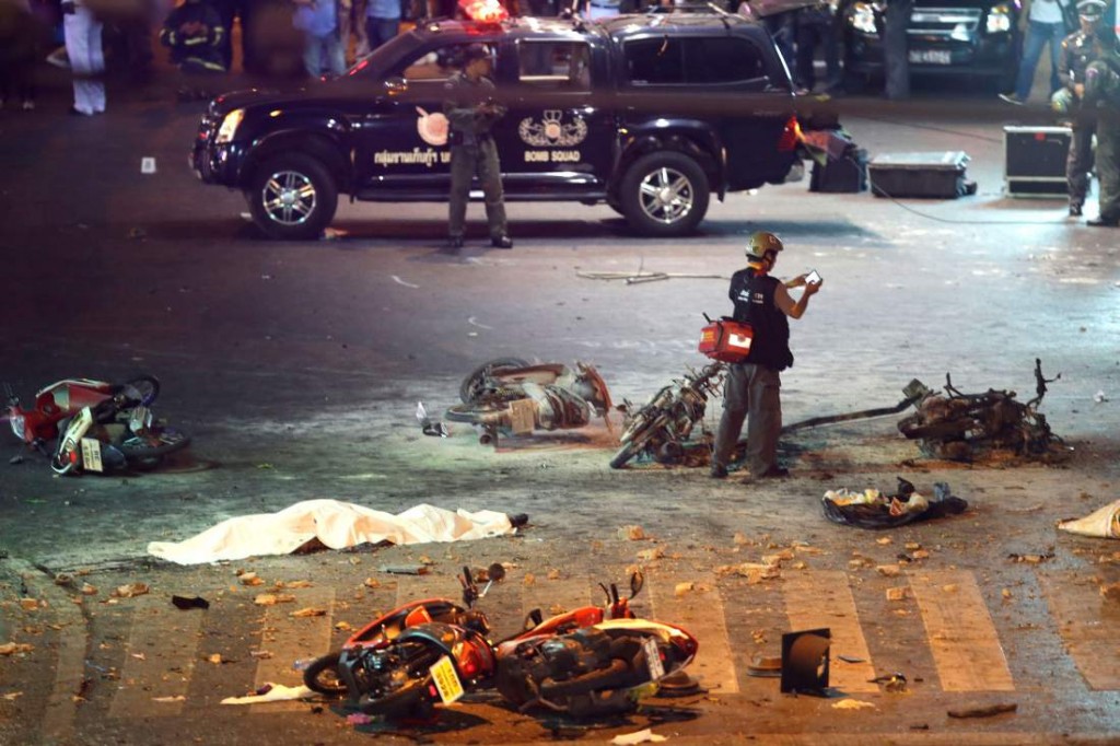 A policeman photographs debris from an explosion in central Bangkok, Thailand, Monday, Aug. 17, 2015. A large explosion rocked a central Bangkok intersection during the evening rush hour, killing at least three people and injuring 25 others, police said. (AP Photo/Mark Baker)